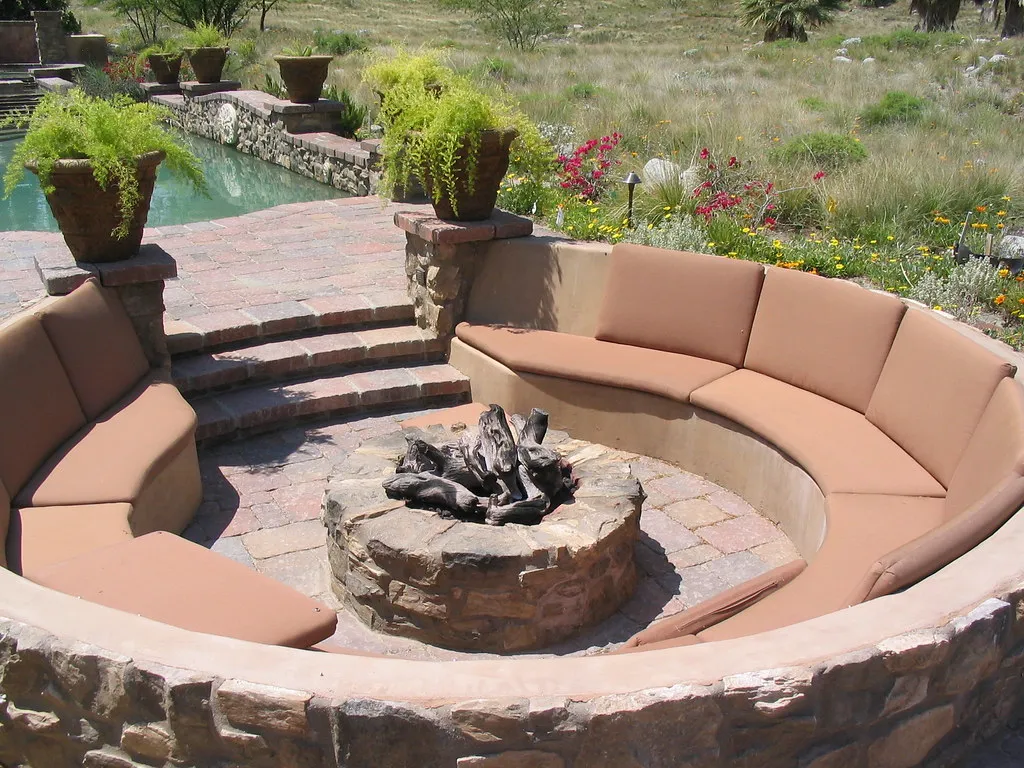 fire pit black logs surrounded with sofas and pool at side