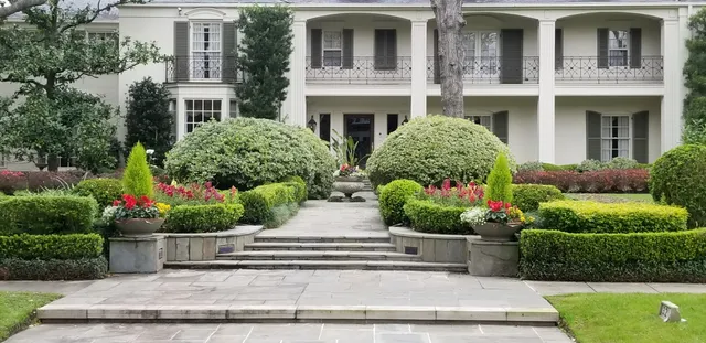 Formal front garden with flagstone steps, clipped boxwood hedges and flowering urns