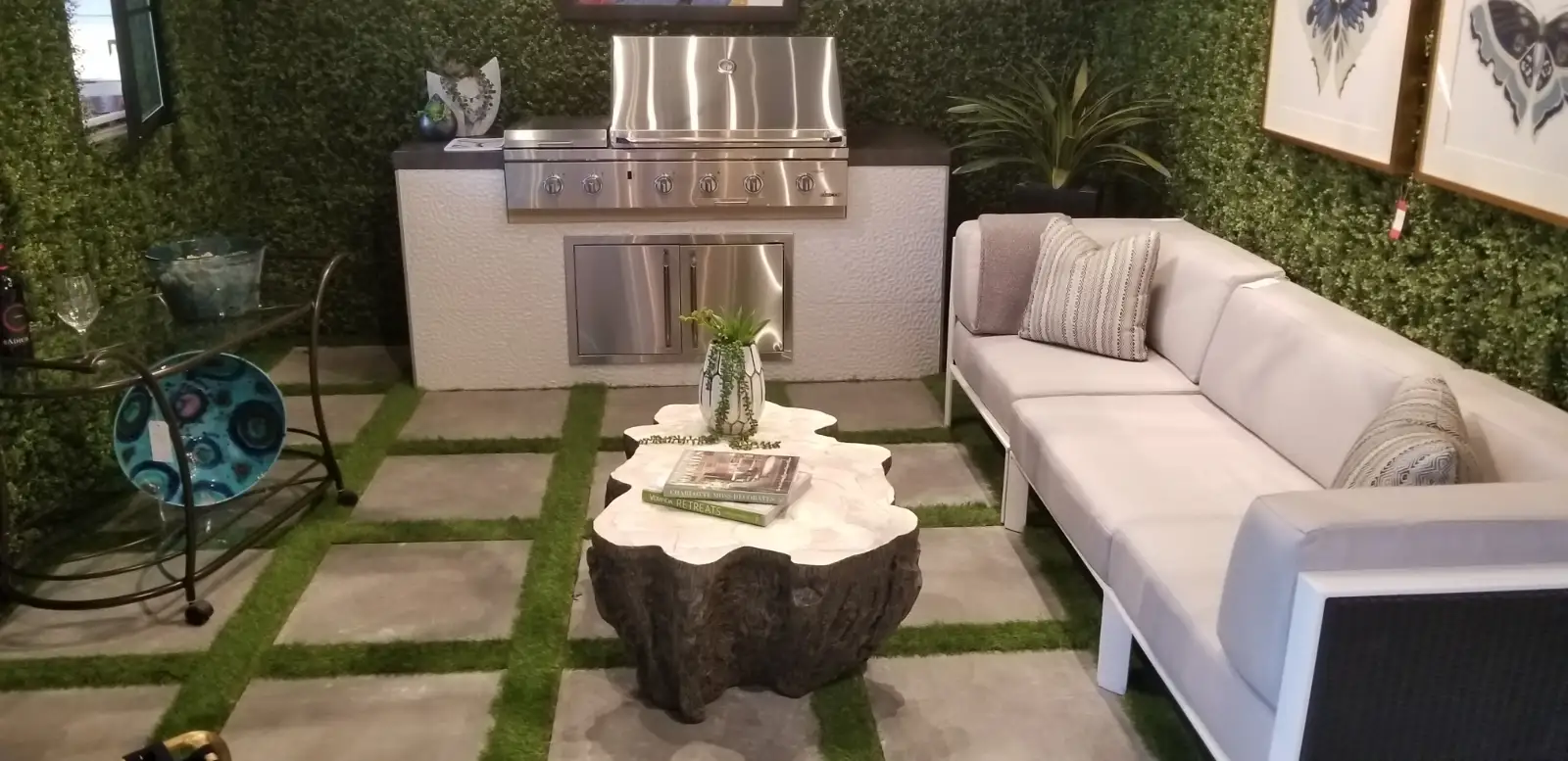 Artificial turf strips set between large concrete pavers around a built-in grill and lounge seating