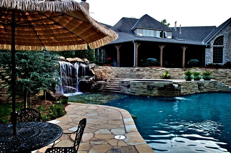 stone paved side pool patio and backyard fountain