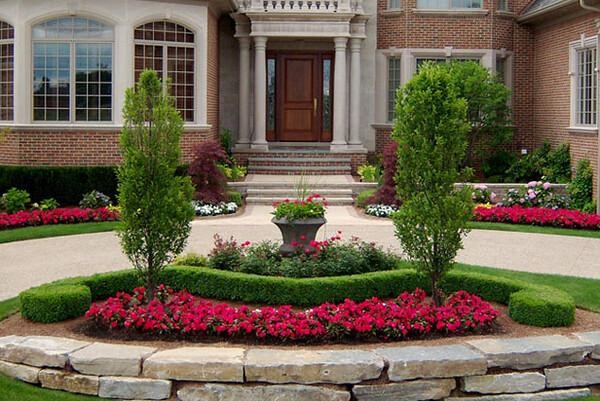 red flowers manicured infront of a big house